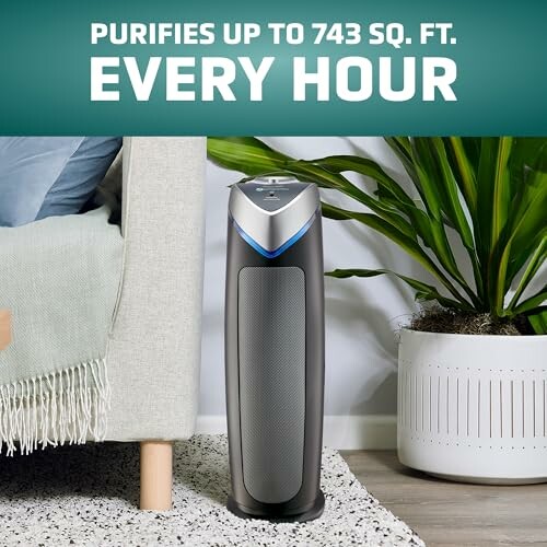 Air purifier in a living room next to a plant and a couch.