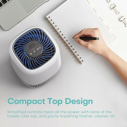 Person writing in notebook near compact air purifier.