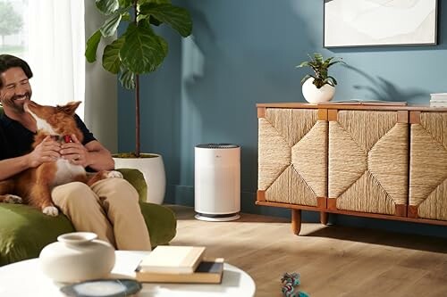 Man sitting on a couch with a dog in a modern living room.