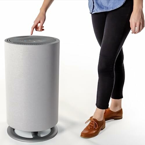 Person adjusting a modern cylindrical air purifier.